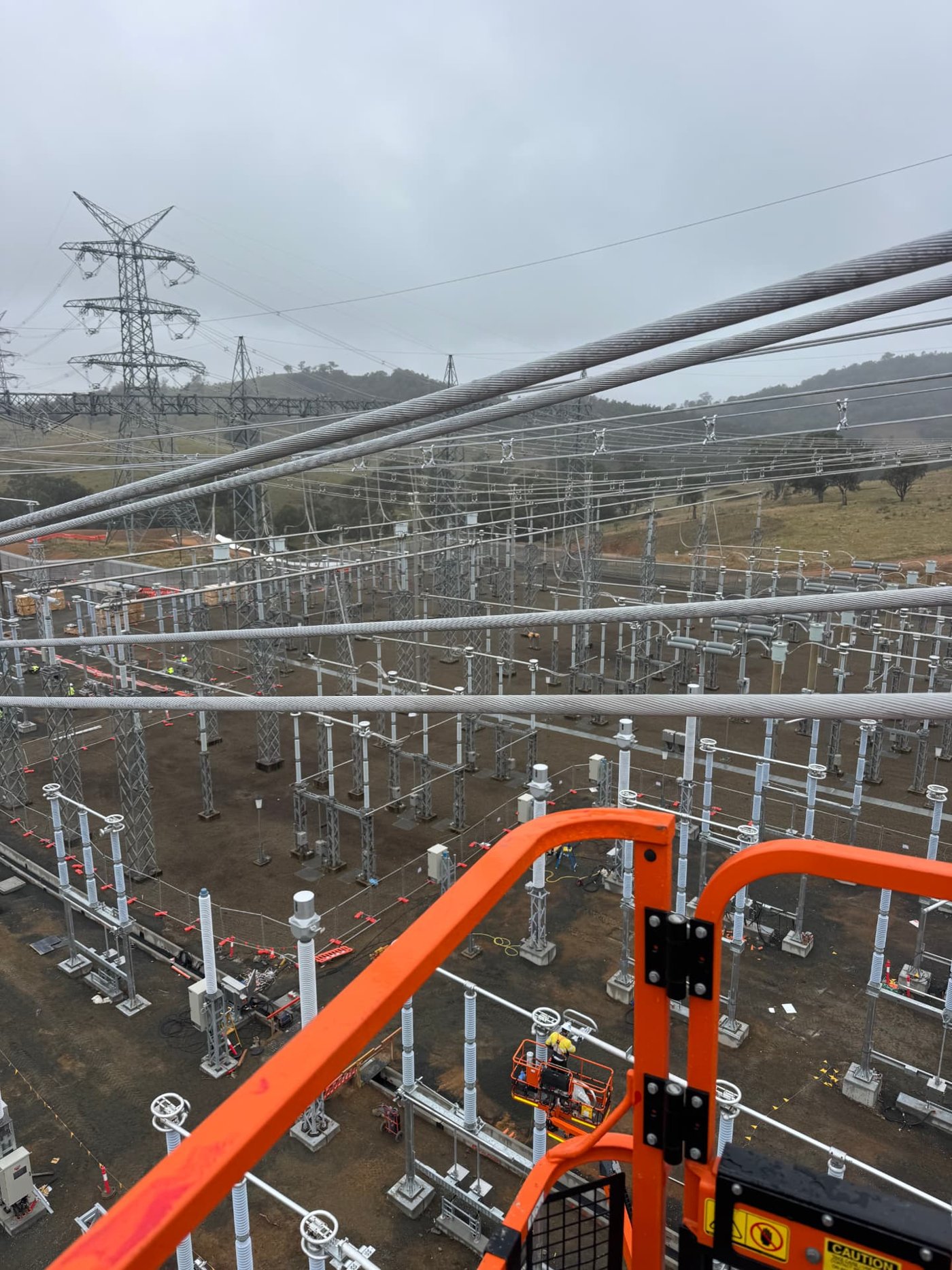 High-voltage transmission substation viewed from an elevated work platform, showing busbar strings and switchgear