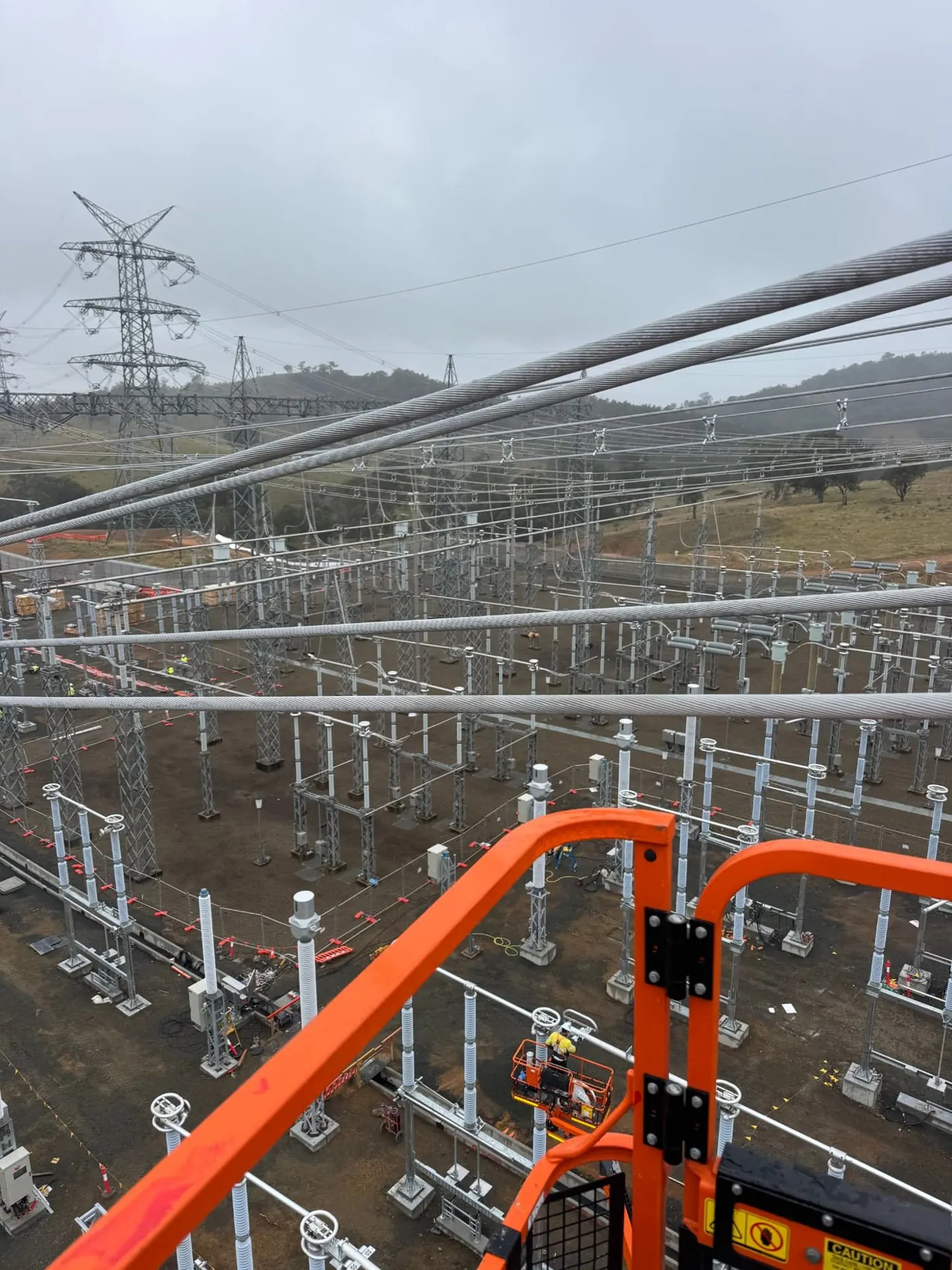 High-voltage transmission substation viewed from an elevated work platform, showing busbar strings and switchgear